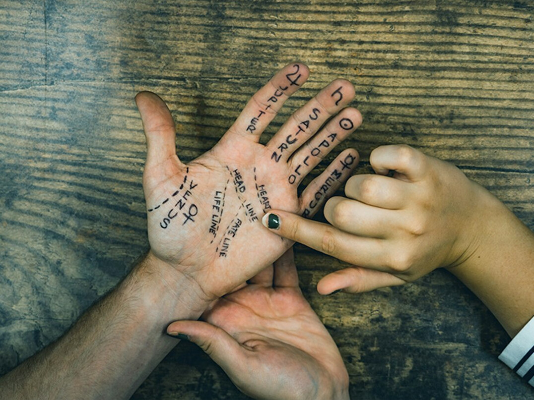 Hands stacked together over a wooden table symbolising partnership